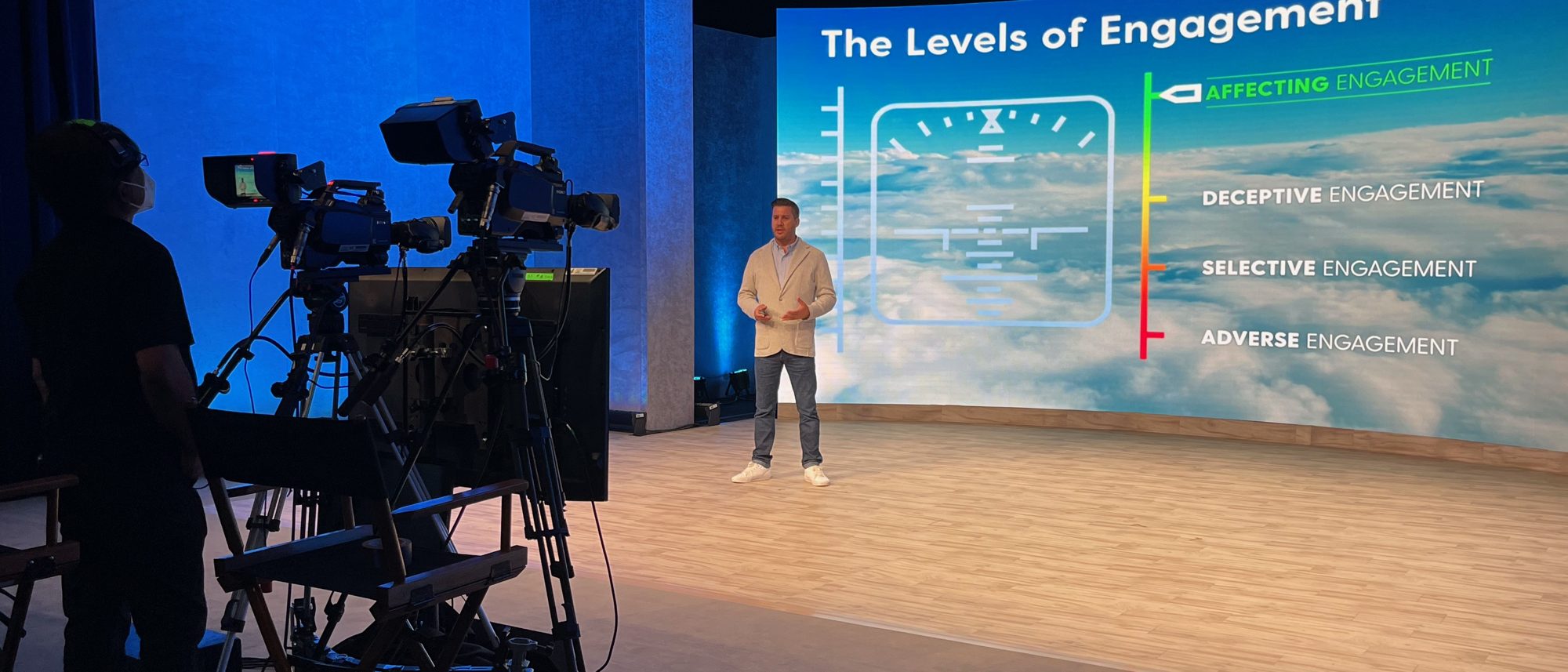 Ben Moorsom in a broadcast studio in front of a slide titled The Levels of Engagement, from Adverse to Affecting