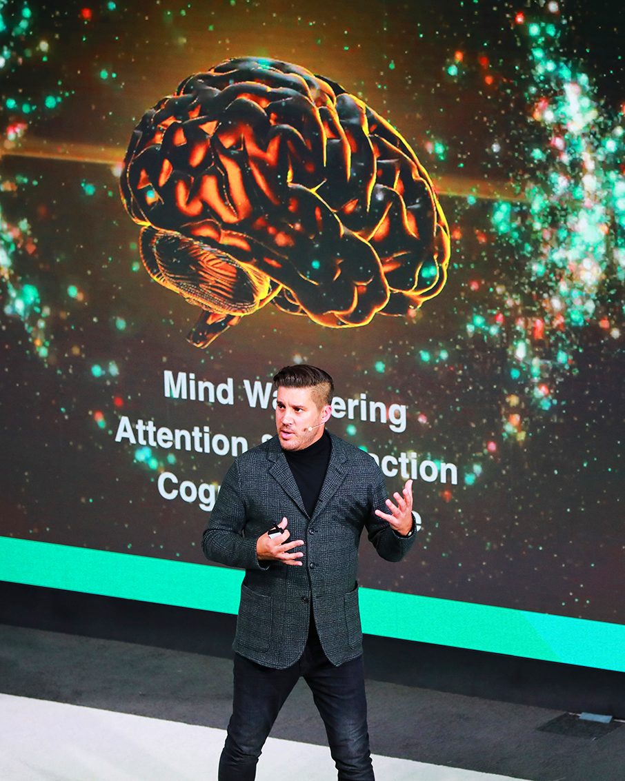 Ben Moorsom presenting Neuroscaping in front of a large screen showing a brain